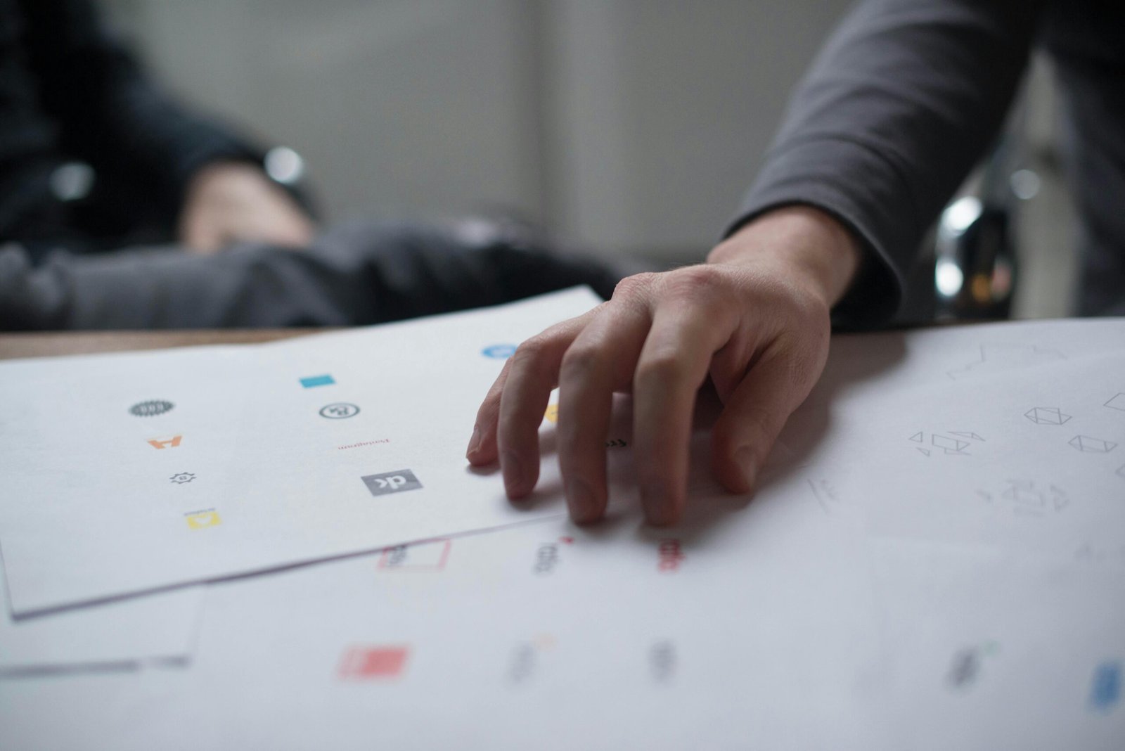 Main sur une feuille présentant des exemples de logos